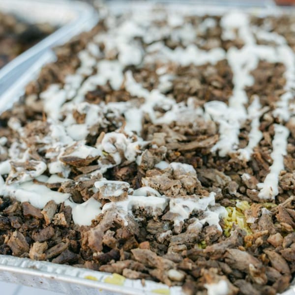 Close-up of Tasa2Go's Egyptian shawarma, with meat and white sauce in a foil tray.